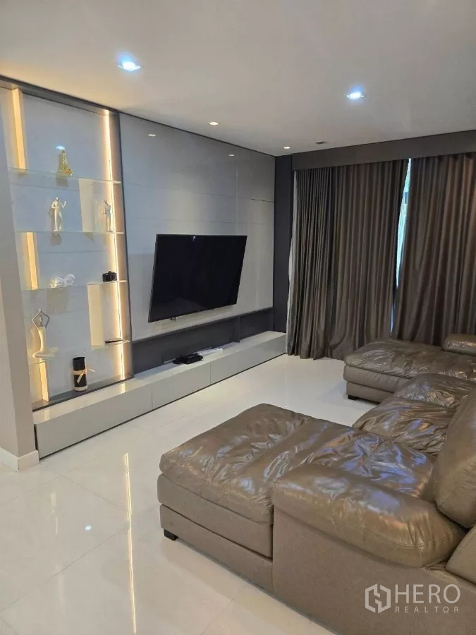 บ้าน ให้เช่าหรือขายในBang Phli, Samut Prakan - ห้องนั่งเล่นอบอุ่น โซฟาเข้ามุม โทรทัศน์ติดผนัง และชั้นโชว์ไฟซ่อน
