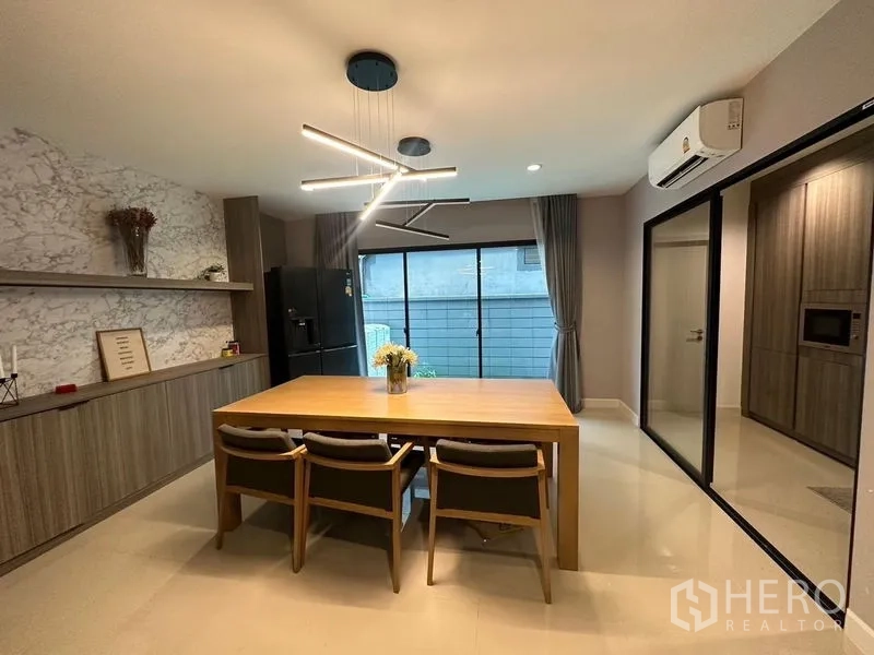 联排别墅 出售在Saphan Sung, Bangkok - 餐厅配现代吊灯与木质餐桌，滑门连接厨房。