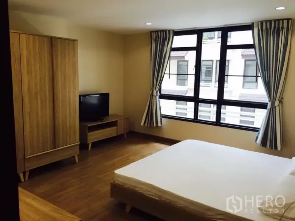 公寓 出租在Watthana, Bangkok - 宽敞卧室，大窗、双人床、木质衣柜与电视柜