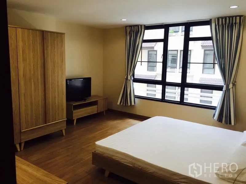 公寓 出租在Watthana, Bangkok - 宽敞卧室，大窗、双人床、木质衣柜与电视柜