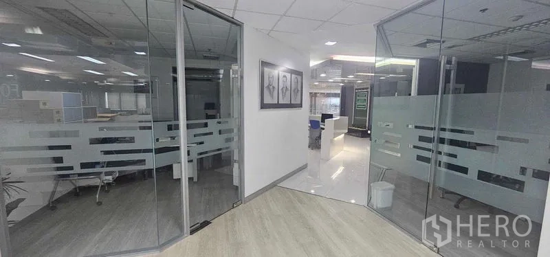 Office Space for rent in Bang Rak, Bangkok - Lobby-style hallway leading to glass-partitioned offices with natural light and wood floors.