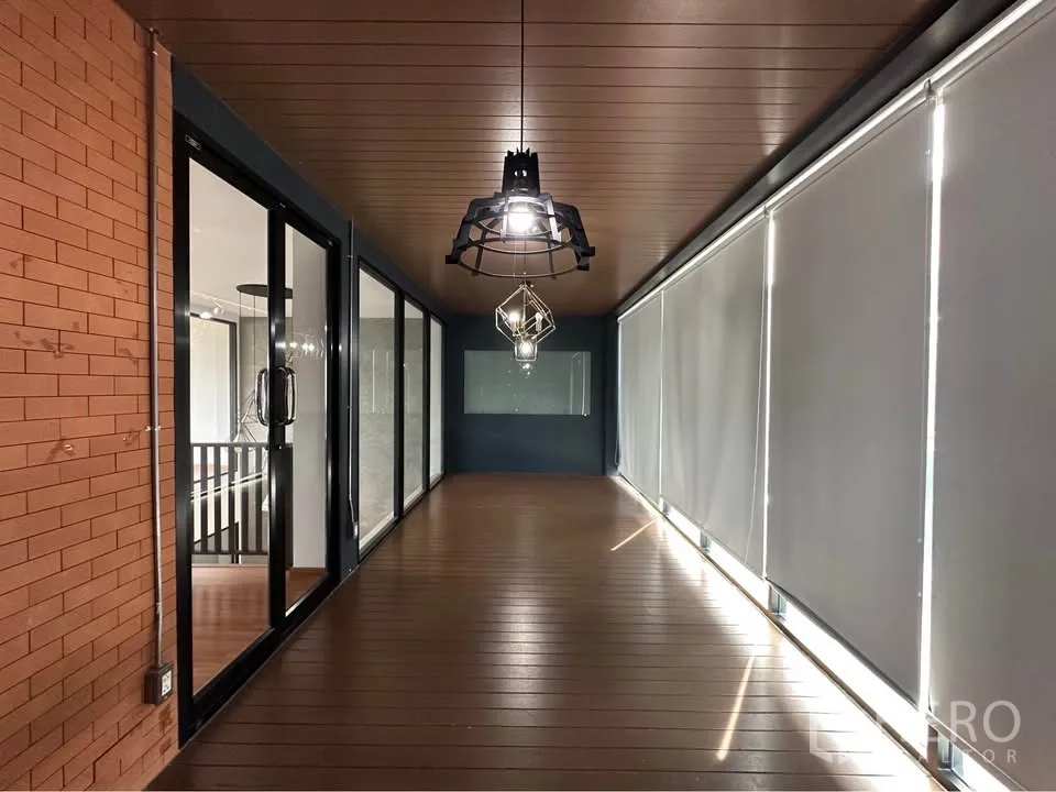 联排别墅 出租在Pak Kret, Nonthaburi - 封闭式阳台走廊，木质天花、吊灯与卷帘。