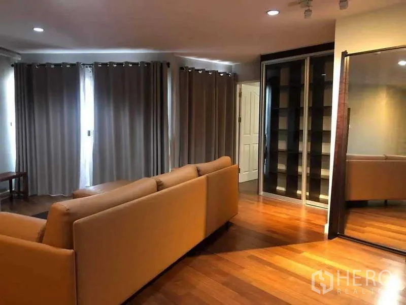 Condominium for sale in Yan Nawa, Bangkok - Living area with floor-to-ceiling curtains and a glass display cabinet.