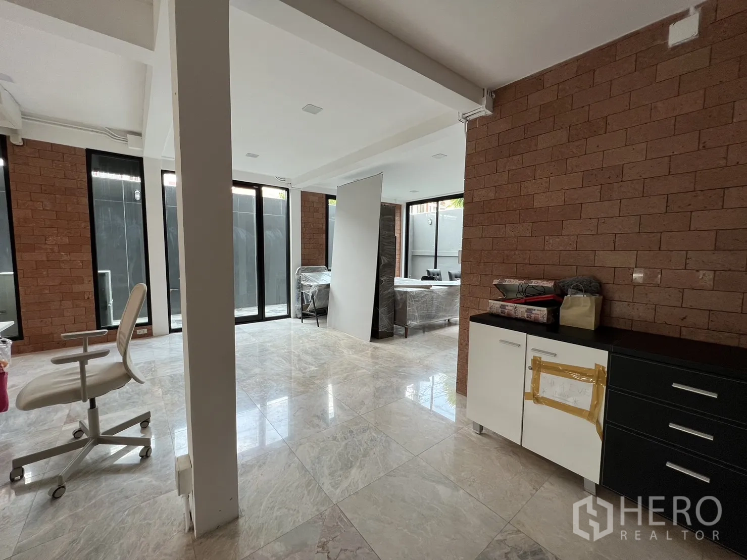 Detached House for rent or sale in Phra Khanong, Bangkok - Ground floor open space with brick feature wall and study corner.