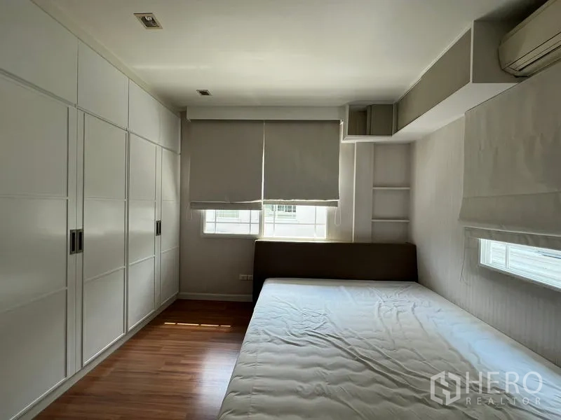 Detached House for rent in Bang Kapi, Bangkok - Bedroom with wall-length white wardrobes and large windows.