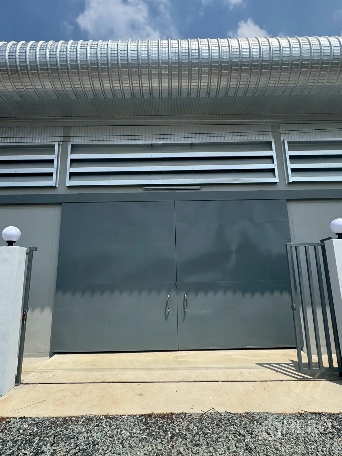 Warehouse for rent or sale in Nong Chok, Bangkok - Close-up of secure double steel doors and ventilation panels on a newly built warehouse facade.