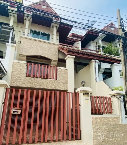 联排别墅 出租在Prawet, Bangkok - 曼谷三层联排别墅外观，红色金属大门与阳台。
