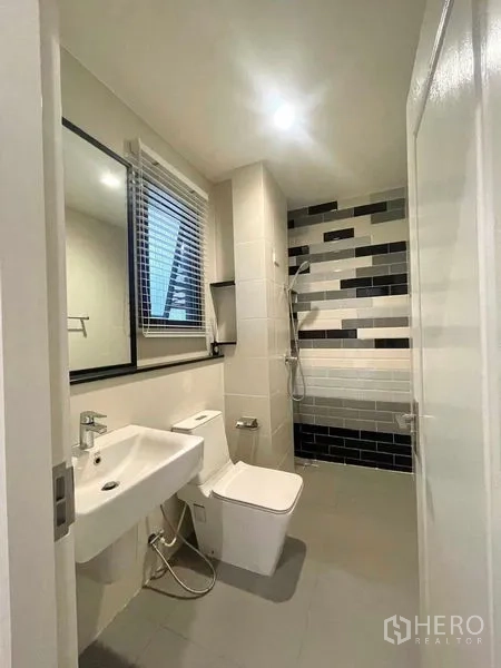 Detached House for sale in Bang Kruai, Nonthaburi - Bathroom with walk‑in shower, black‑and‑white feature wall tiles, toilet and vanity mirror.