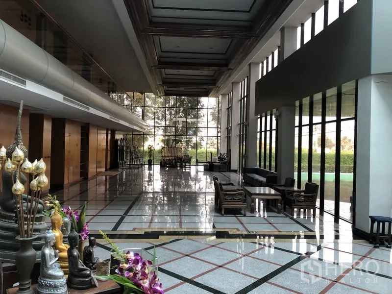 Factory for rent in Bang Bua Thong, Nonthaburi - Grand lobby with full‑height glass, lounge seating, and polished floors overlooking greenery.