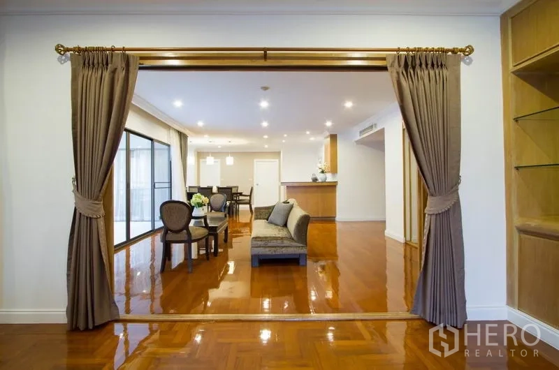 Condominium for rent in Watthana, Bangkok - Open-plan living and dining room with glossy wood floors and recessed lighting.