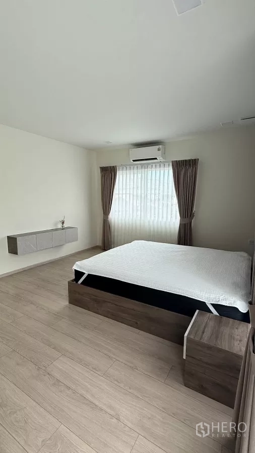 Detached House for rent in Bang Phli, Samut Prakan - Master bedroom with double bed, wood flooring, and window drapes.