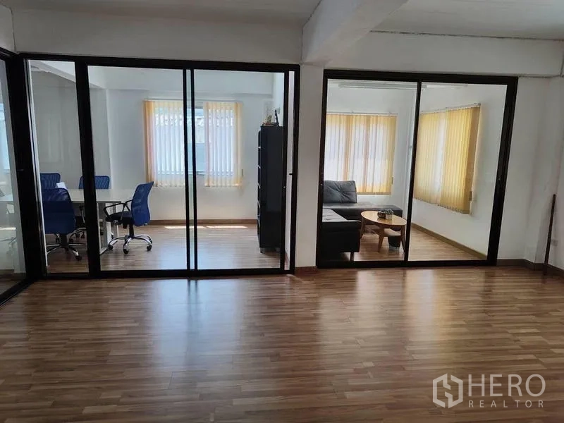 Factory for sale in Sai Noi, Nonthaburi - Bright office rooms with sliding glass partitions and laminate wood floors.
