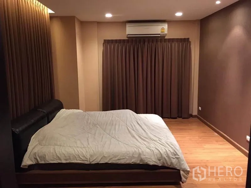Detached House for rent or sale in Khlong Toei, Bangkok - Spacious master bedroom with wood flooring, padded bed, air conditioner and blackout curtains.