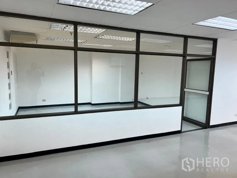 办公空间 出租在Pathum Wan, Bangkok - 白色办公区内的玻璃会议室，吊顶灯光与亮面地坪。