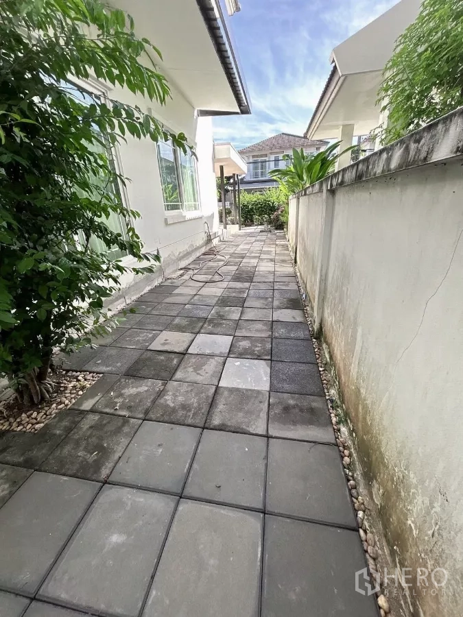 Detached House for sale in Bang Kapi, Bangkok - Side walkway with concrete pavers and garden wall alongside the house.