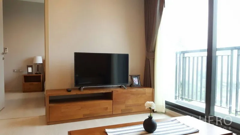 Condominium for rent in Khlong Toei, Bangkok - TV cabinet facing floor-to-ceiling glass doors that open to the balcony.