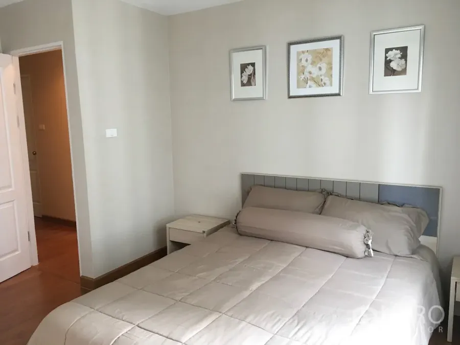คอนโด ให้เช่าในHuai Khwang, Bangkok - ห้องนอนโทนอบอุ่น เตียงผ้าปูสีเบจและภาพติดผนังสามกรอบ