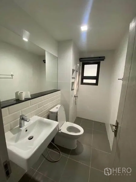Detached House for rent or sale in Saphan Sung, Bangkok - Clean bathroom with large mirror, white sink and tiled floor.