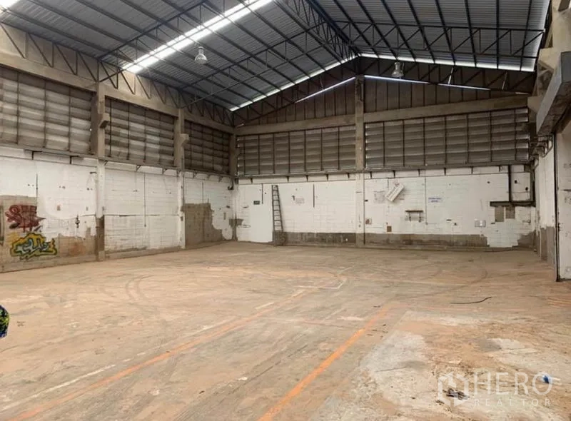Warehouse for rent in Samut Prakan - Open production floor with high ceilings, ventilated louvered walls, and durable concrete flooring.