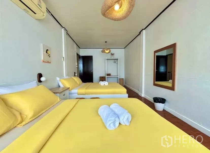 联排别墅 出租在Watthana, Bangkok - 客卧配两张黄色床，吊灯与全身镜