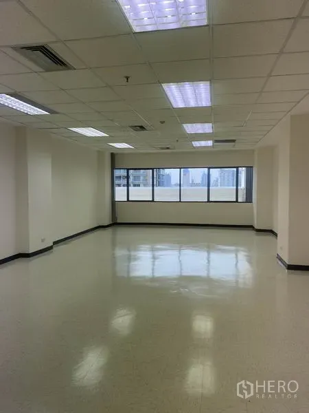 办公空间 出租在Watthana, Bangkok - 明亮的开放式办公区，宽幅窗户、城市景观、格栅吊顶与荧光照明