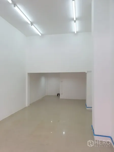 Shophouse for rent in Khlong Toei, Bangkok - Long narrow retail space with tiled floor, white walls and rear storage nook.