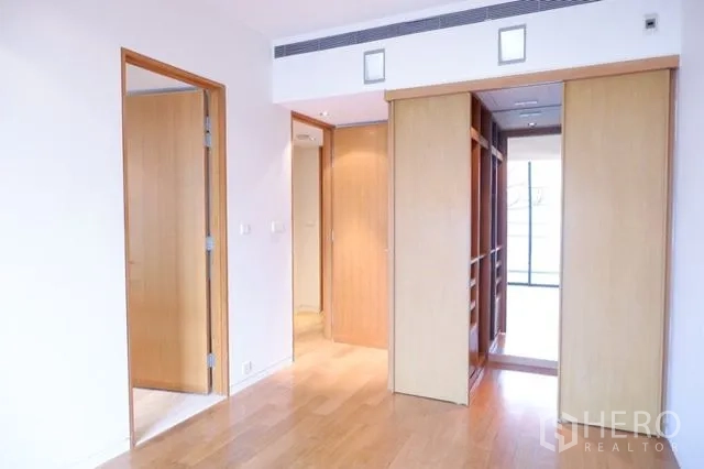 Condominium for sale in Sathon, Bangkok - Primary bedroom featuring built-in walk-in closet and warm wood finishes.