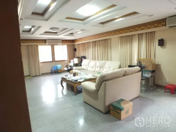 独立式住宅 出租在Bang Rak, Bangkok - 宽敞客厅，层次天花、米色转角沙发与亮面石地板。