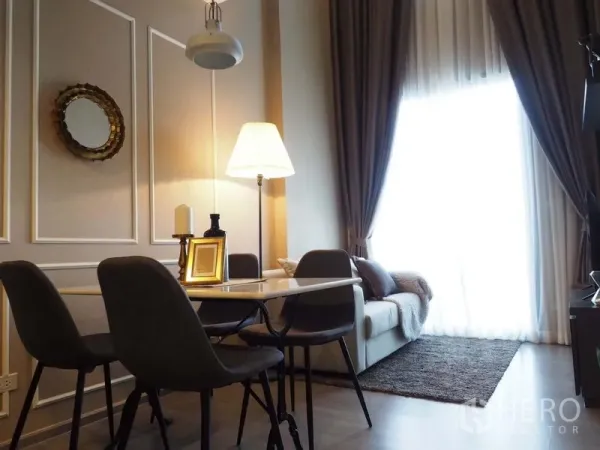 Condominium for rent in Khlong San, Bangkok - Dining area with four-seat table beside the living room and a large curtained window providing natural light.