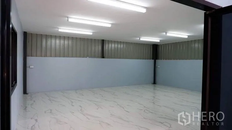 Warehouse for rent in Bueng Kum, Bangkok - Bright warehouse office room with marble-look tile floors and strip lighting.