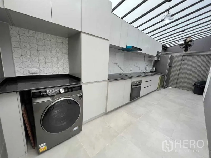 联排别墅 出租在Wang Thonglang, Bangkok - 采光天窗封闭式厨房，整排柜体、黑色台面，配洗烘一体机。