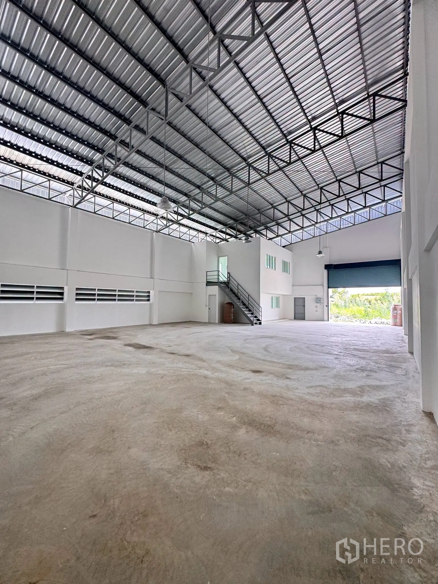 Warehouse for rent in Bang Bo, Samut Prakan - View toward the large roller shutter at the loading area and the mezzanine stairs.