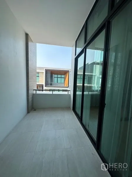 联排别墅 出售在Saphan Sung, Bangkok - 有顶阳台，玻璃栏杆，眺望对面现代联排别墅。