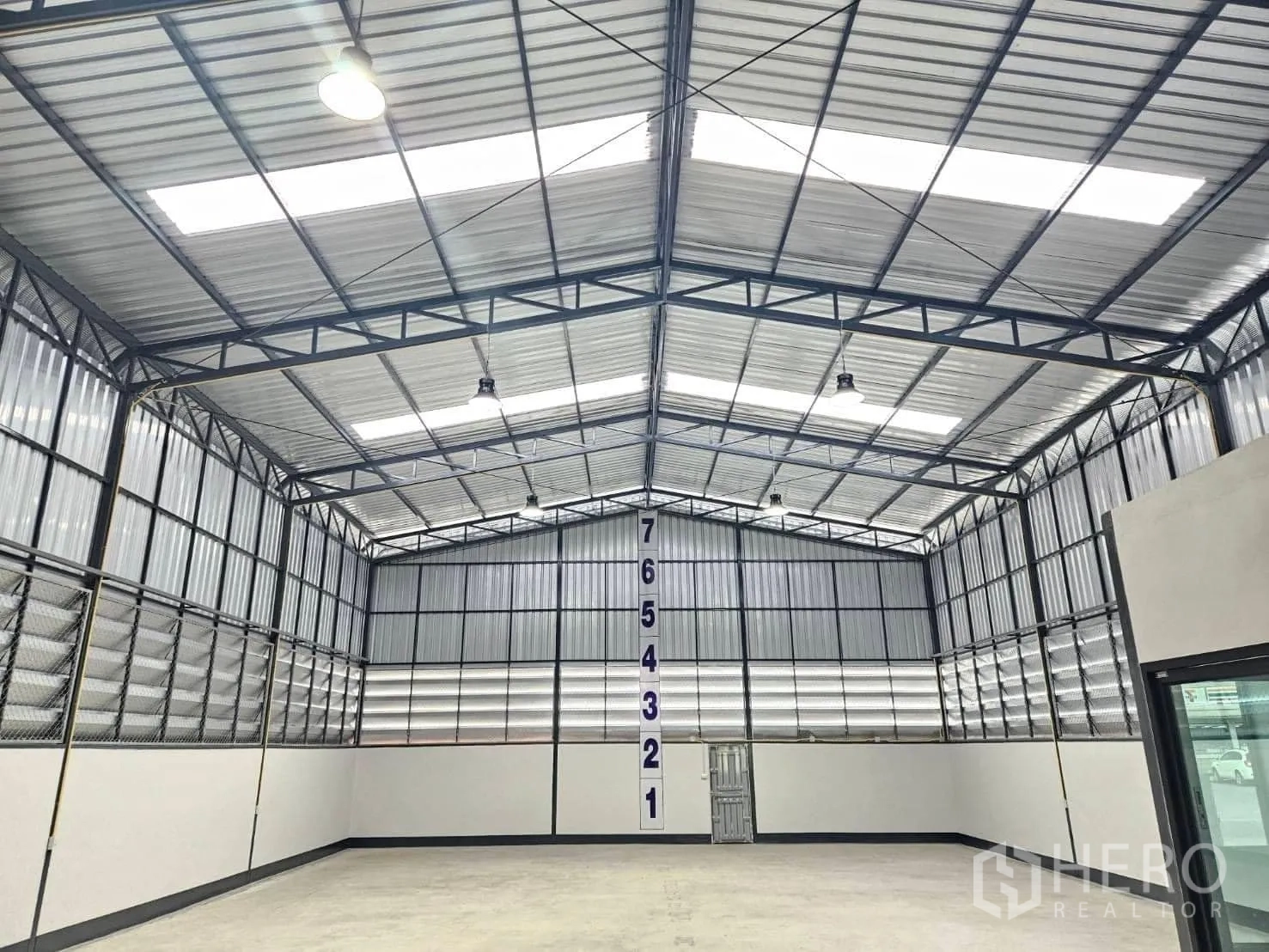货栈 出租在Lam Luk Ka, Pathum Thani - 屋顶桁架与采光带特写，墙面有高度标记。