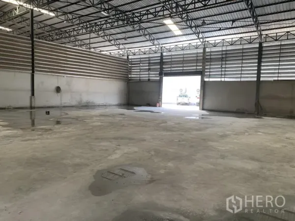 Warehouse for rent in Bueng Kum, Bangkok - Open-plan warehouse space with wide roller shutter entrance and ventilated louvered walls.
