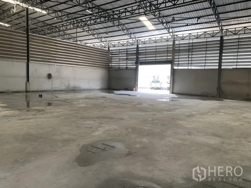 Warehouse for rent in Bueng Kum, Bangkok - Open-plan warehouse space with wide roller shutter entrance and ventilated louvered walls.
