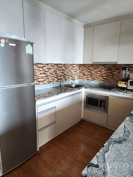 Condominium for rent in Bang Rak, Bangkok - Modern L‑shaped kitchen with granite countertops, mosaic backsplash, stainless refrigerator and built‑in microwave.