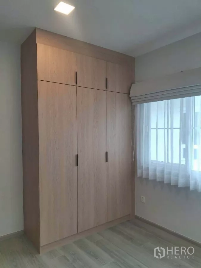 Detached House for rent or sale in Bang Phli, Samut Prakan - Bedroom corner with full-height wooden wardrobe and window.