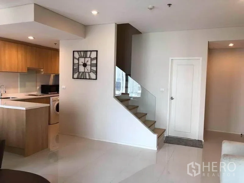 公寓 出租在Ratchathewi, Bangkok - 玻璃栏杆楼梯通往夹层，俯瞰厨房与客厅