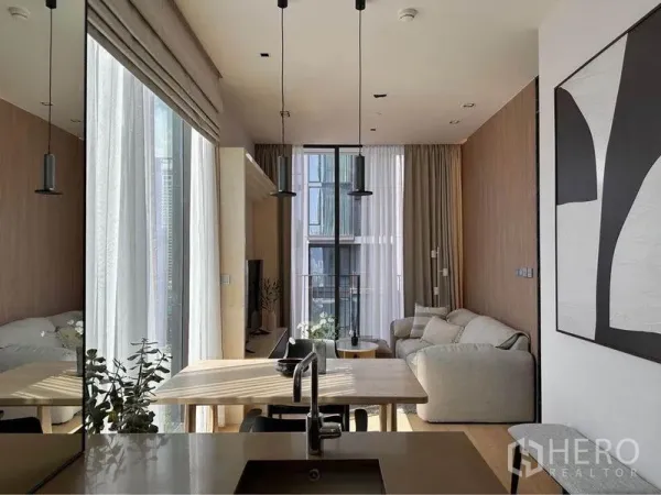 Condominium for rent in Pathum Wan, Bangkok - Open-plan kitchen facing the dining table and lounge with pendant lights and full-height glazing.