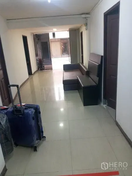 Retail Space for rent in Khlong Toei, Bangkok - Bright corridor with tiled floor, brown sofa and multiple doors leading to rooms.