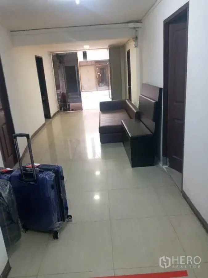 Retail Space for rent in Khlong Toei, Bangkok - Bright corridor with tiled floor, brown sofa and multiple doors leading to rooms.