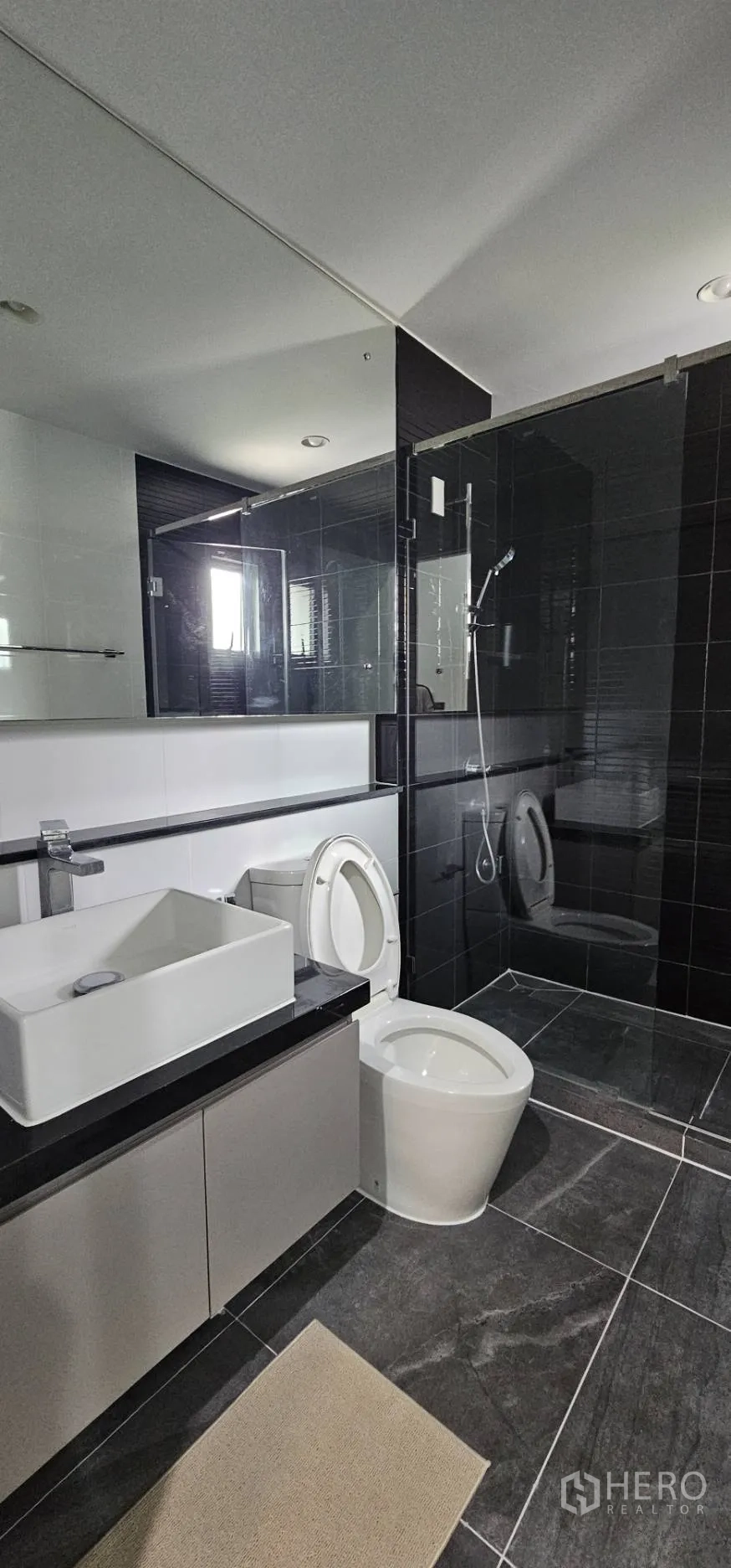 Detached House for rent in Bang Kapi, Bangkok - Contemporary bathroom with glass shower, vanity and black tiles.