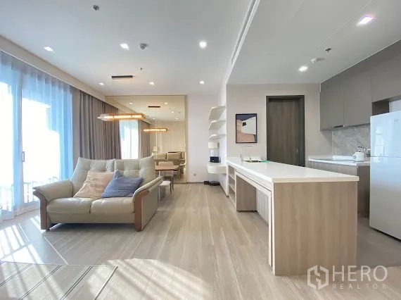คอนโด for rent in Bang Kho Laem, Bangkok - ห้องนั่งเล่นและครัวแบบเปิดสว่าง มีเคาน์เตอร์ไอส์แลนด์ โซฟา โต๊ะทานอาหาร และหน้าต่างสูงจรดเพดานในคอนโดโมเดิร์น