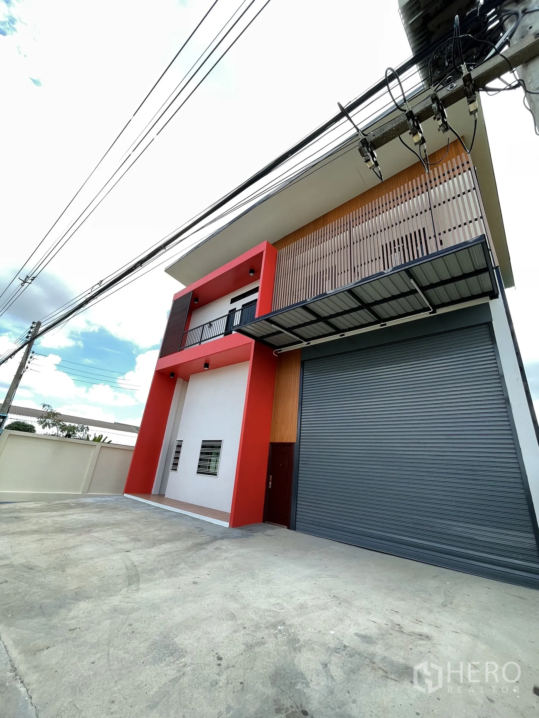 Factory for rent or sale in Lam Luk Ka, Pathum Thani - Modern exterior with vertical slat cladding, canopy, and high roller door for truck access.