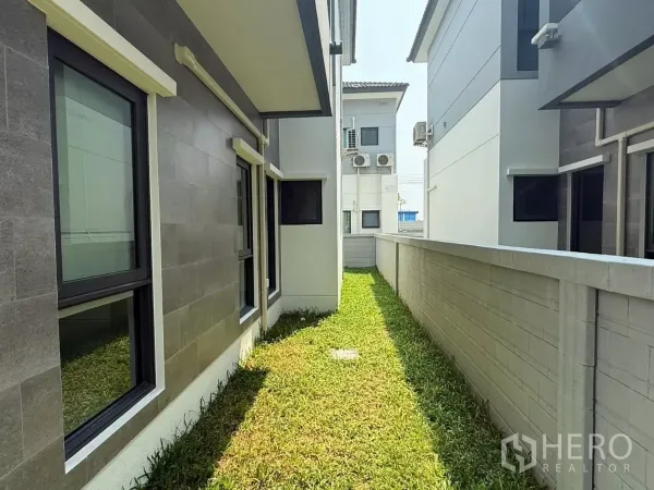 独立式住宅 出租在Bang Phli, Samut Prakan - 房屋侧院狭长草地，外墙窗户与围墙相对