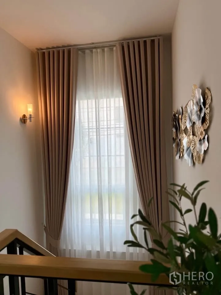 Semi-detached House for rent in Mueang Samut Prakan, Samut Prakan - Stair landing with tall curtained window and wall sconce lighting.
