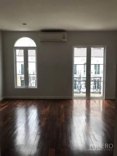 联排别墅 出租在Watthana, Bangkok - 卧室带拱形窗与阳台门，可望小区景致