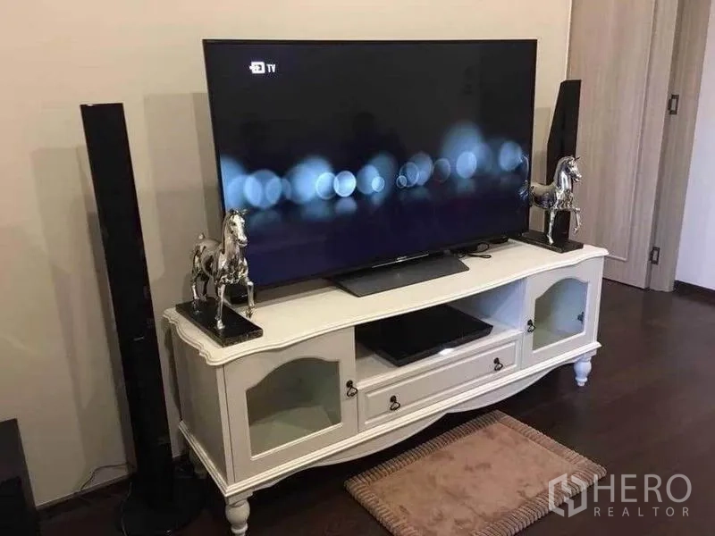 Condominium for rent in Watthana, Bangkok - Flat-screen TV on a vintage white console with tall speakers in the living area.