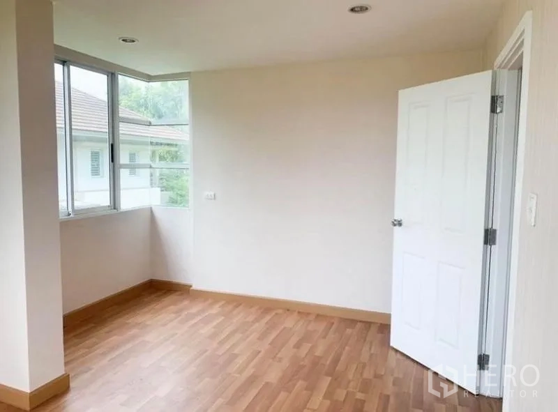 Detached House for sale in Saphan Sung, Bangkok - Another bright corner bedroom with angled window and white door.